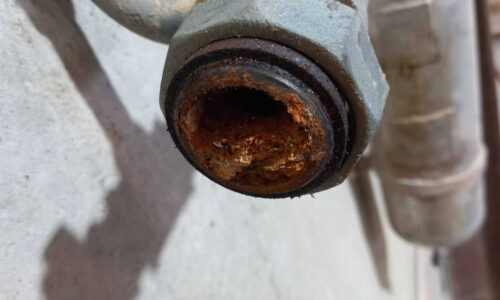 A galvanised air pipe in an industrial compressed air installation. The pipe is clogged with rust flakes.