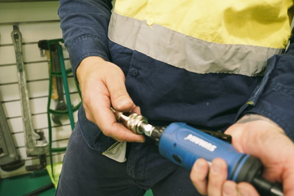 factory worker connecting an infinity air coupling to an air tool