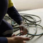 worker wearing hi vis crouching on the floor to connect a coupling to an air hose line